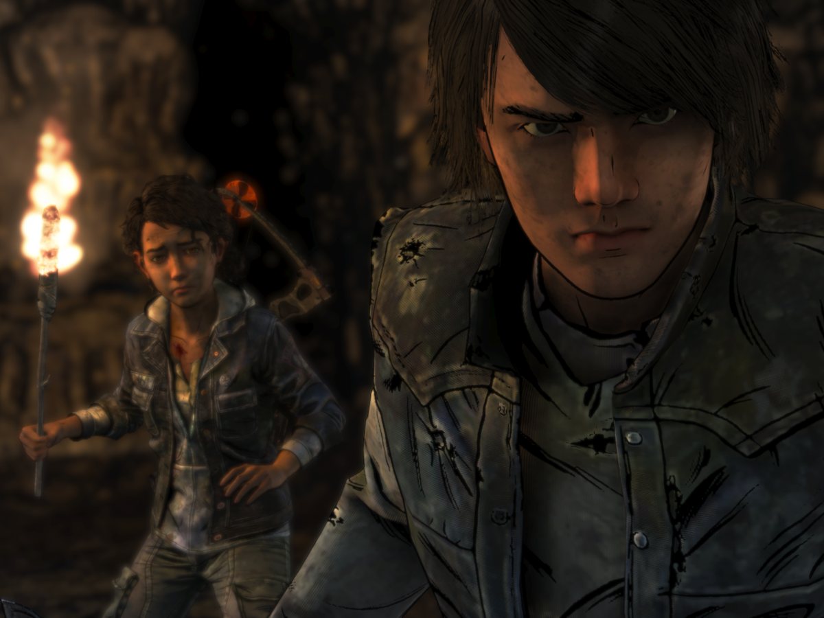 The Walking Dead: The Final Season: Clementine holding a torch behind a boy in a cave